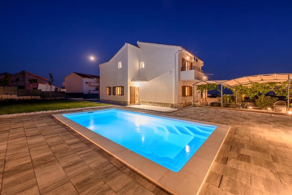 a swimming pool in front of a house at night at Villa Botanica near Split - Heated Pool and Garden in Kučine