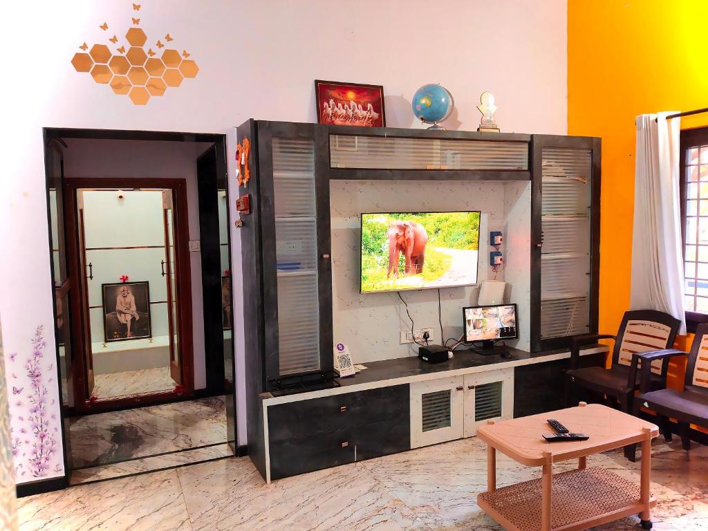 a living room with a flat screen tv on a entertainment center at Keshu Home Stay Hampi in Hospet