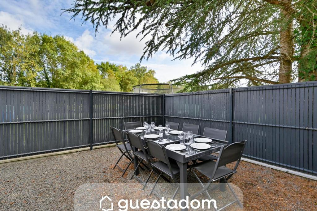 a patio with a table with chairs and a fence at Laurière - Wifi - Parking - Pet friendly in Port-Saint-Père
