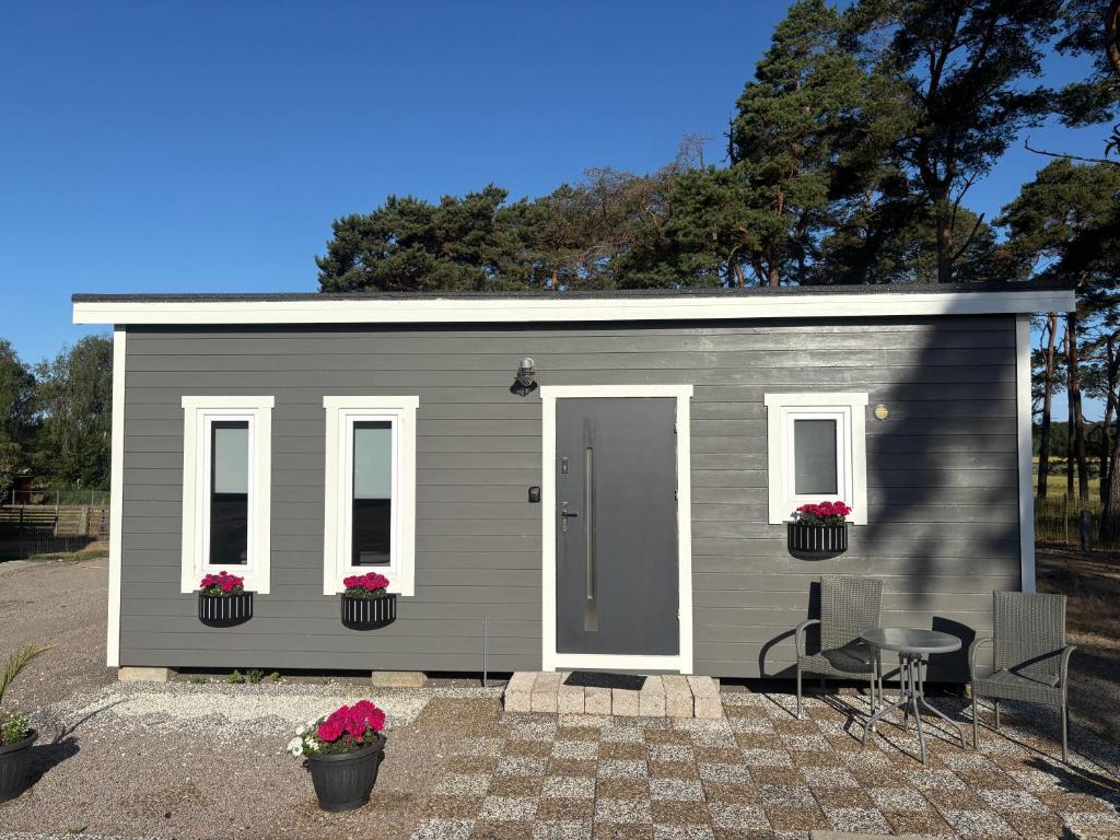 a small gray shed with a table and chairs at Mayas Stuga in Sölvesborg