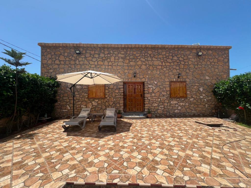 a patio with chairs and an umbrella in front of a building at 5 Min to Beach & Calm Villa Retreat in Safi