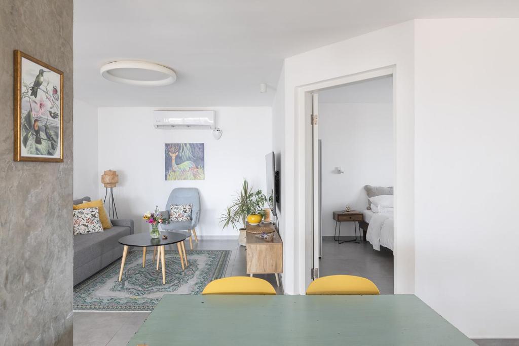 a living room with a table and yellow chairs at לגעת בלב in Yavneʼel