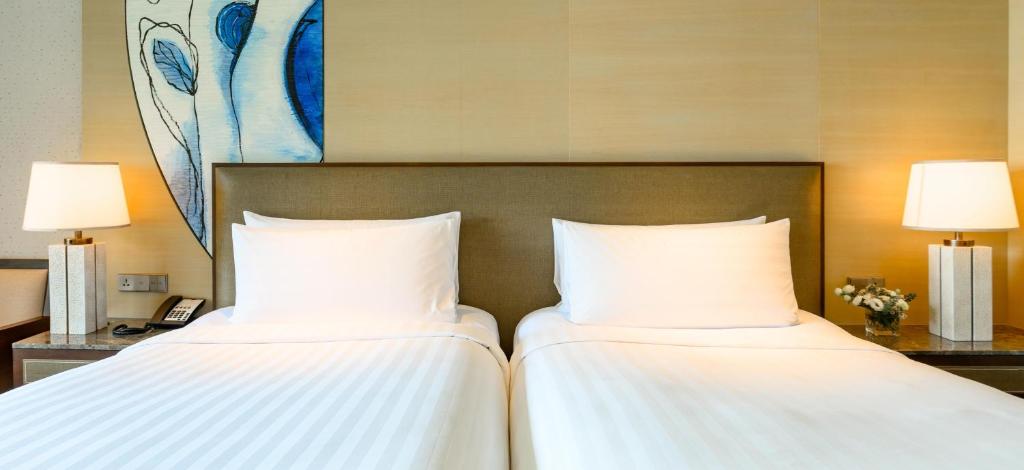 two beds in a hotel room with white sheets at Shangri-La Tanjung Aru, Kota Kinabalu in Kota Kinabalu