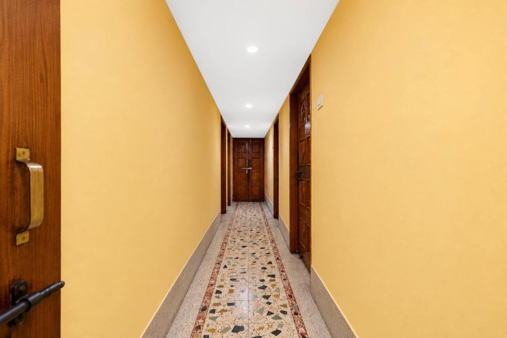 a hallway with yellow walls and a tile floor at SPOT ON Khedia Inn in Bokāro
