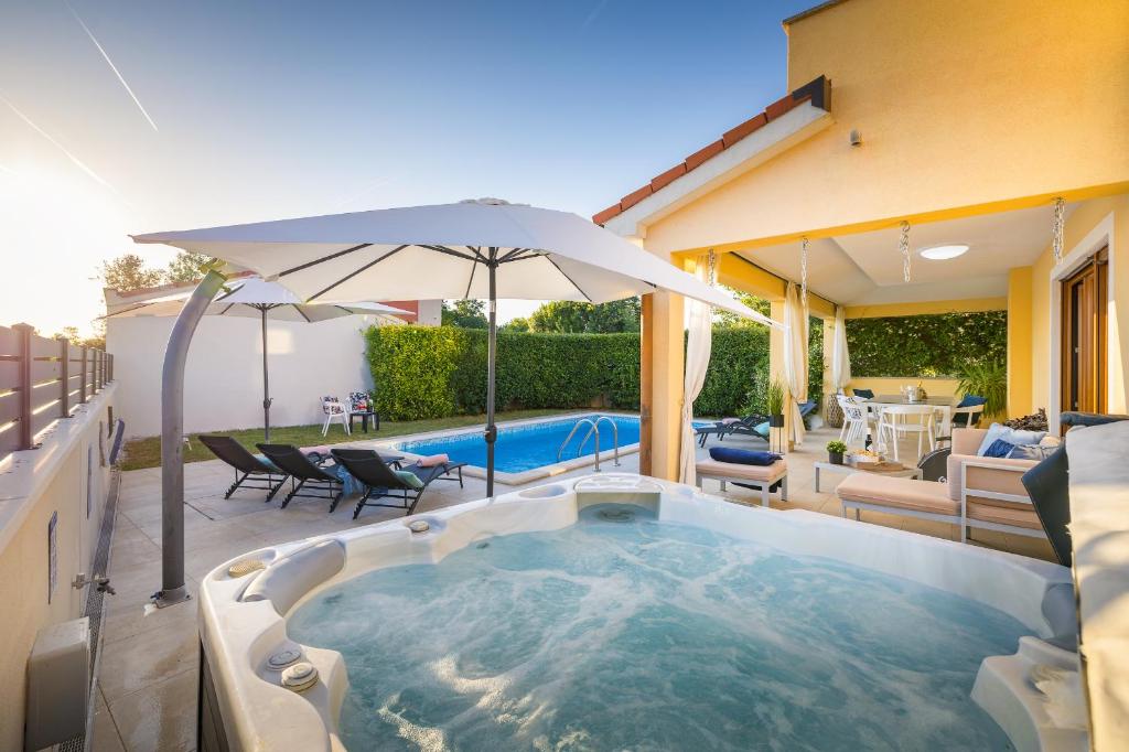 a hot tub on a patio with an umbrella at House with pool and whirlpool in Sarići