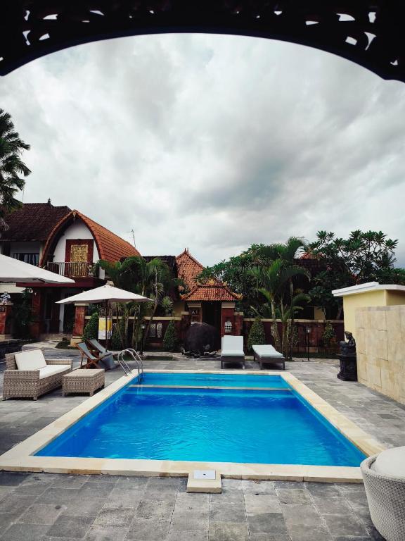 a large blue swimming pool in a yard at Nirmala Guest House Surf Keramas in Keramas