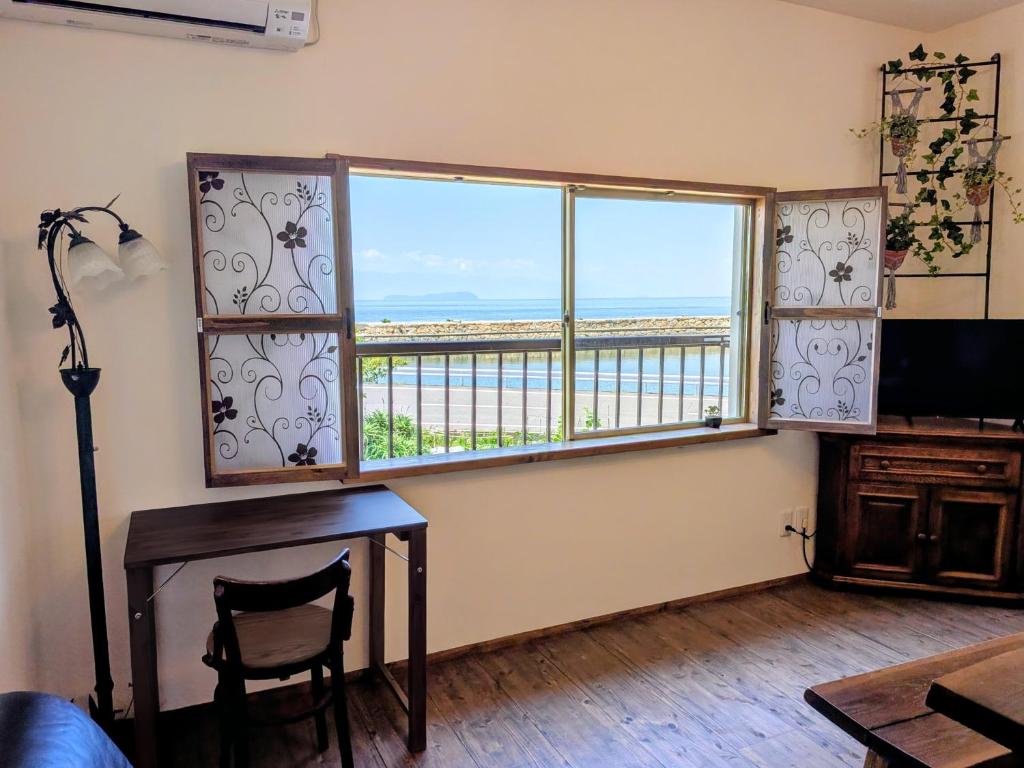 a room with a desk and a window with a view of the ocean at Hatoya in Mitoyo