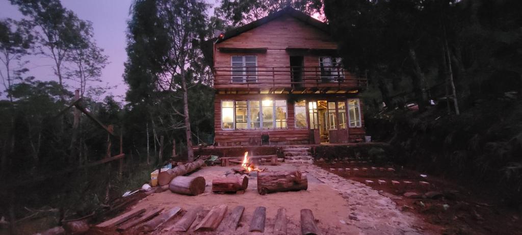 a log house with a fire in front of it at Mộc Tín Farmstay in Lạc Dương