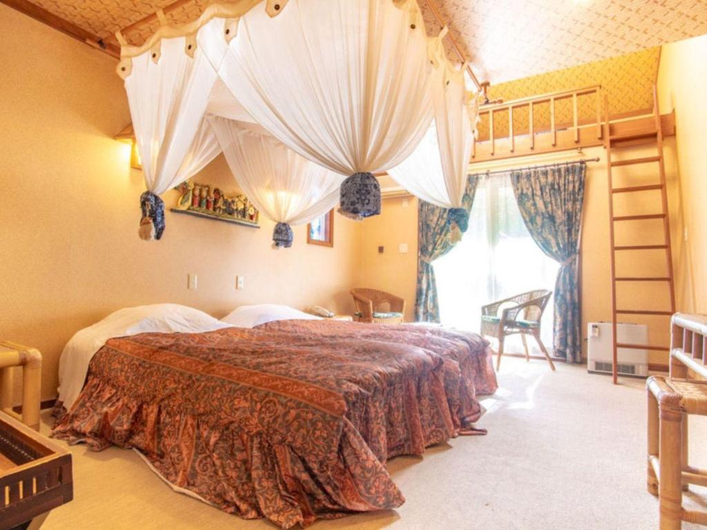 a bedroom with a large bed with curtains at Estivant Club in Tsumagoi