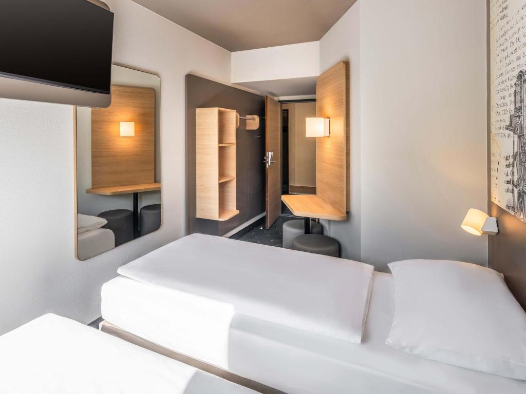 a room with two beds and a mirror at B&B HOTEL Düren in Düren - Eifel