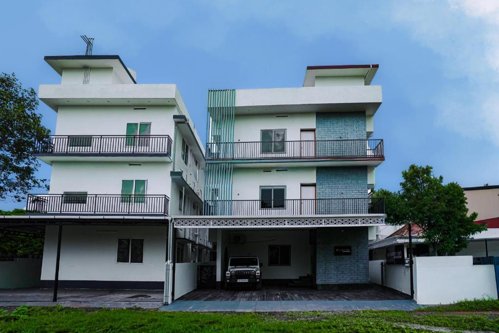 a tall white building with a car parked in front at Uni Stay Inn in Cochin