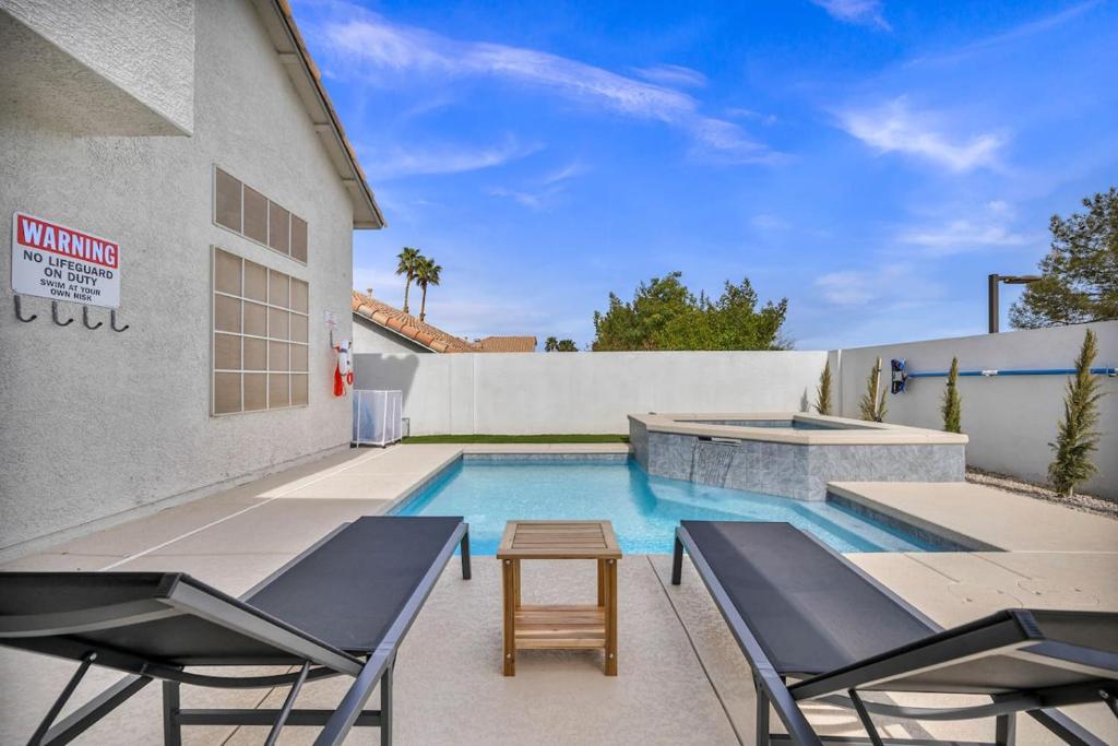 a swimming pool with two chairs and a table next to a building at Vegas Haven Pool Spa Game Room in Las Vegas