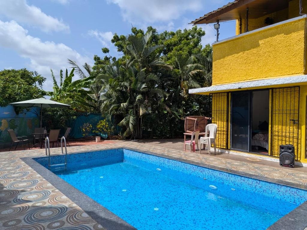 a swimming pool next to a house with a yellow building at Trupti Villa & Cottages-Nagaon- Three BHK Villa in Alibaug