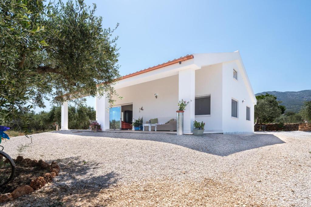 a large white house with a gravel driveway at Villa Piricone in Orosei