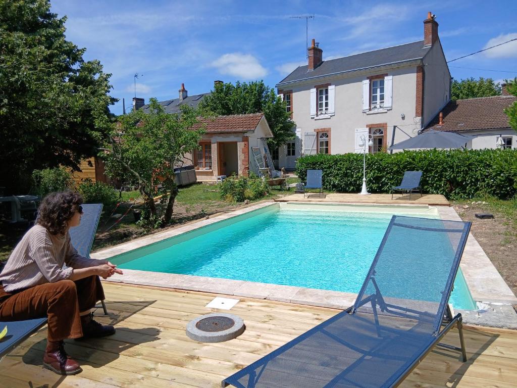 a woman sitting in a chair next to a swimming pool at Jardin sur Loire in Blois