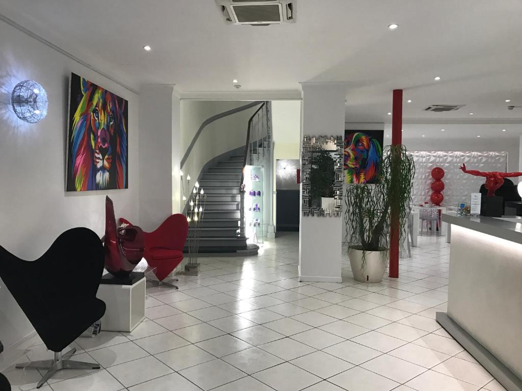 - un hall avec des chaises rouges et un escalier dans l'établissement Hôtel Le Capitole, à Toulouse