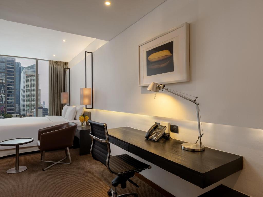 A bedroom workspace with a long desk, office chair, and city-facing window.