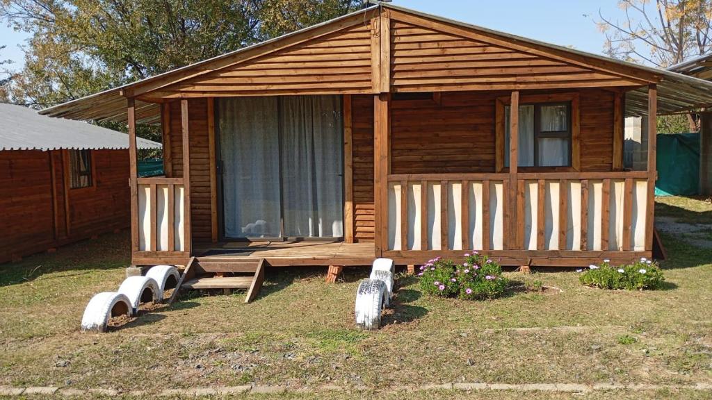 a small wooden cabin with a porch and a window at Wanderlust Bergville in Bergville