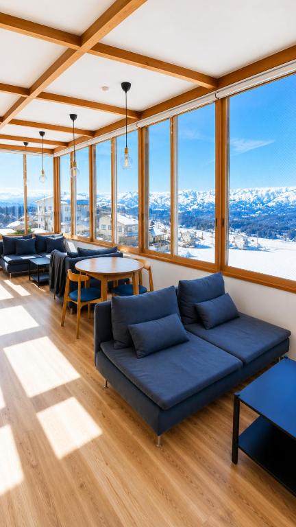 a room with a couch and tables and windows at Snow Palace Nozawa in Nozawa Onsen