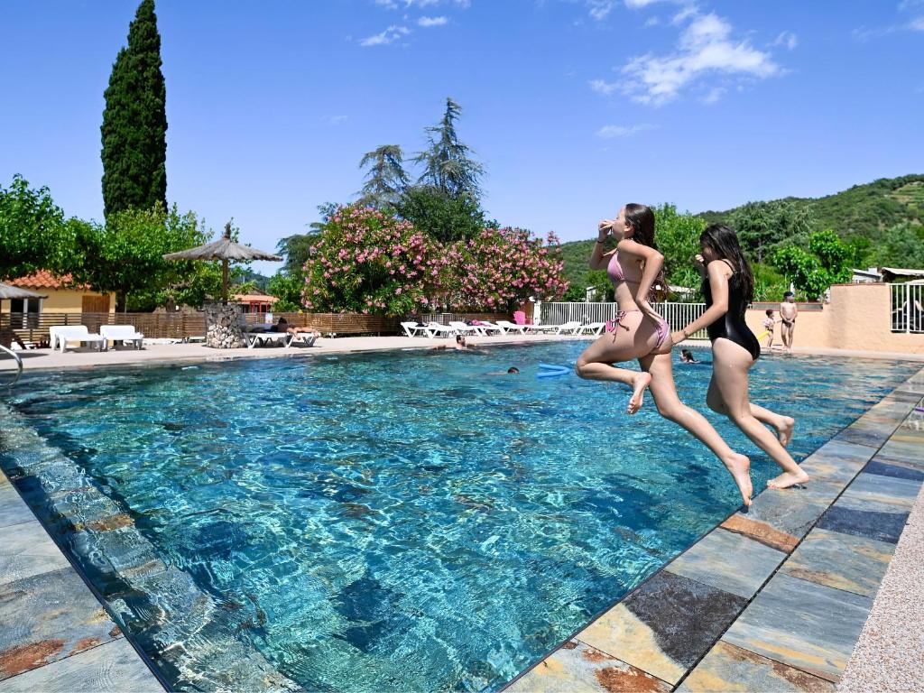 two women jumping into a swimming pool at Aloha Camping Club in Reynès