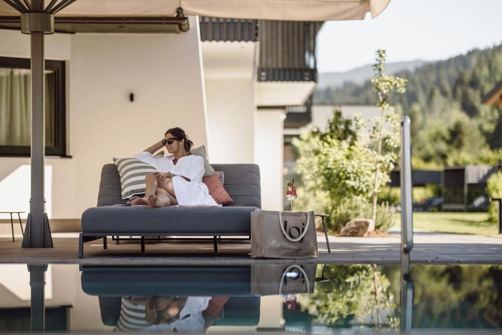 a woman sitting on a couch next to a pool at Hotel loj - our kind of place in Flachau