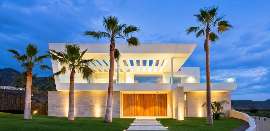 a house with palm trees in front of it at CHALET 95, Lujo y Piscina Infinity in Adeje