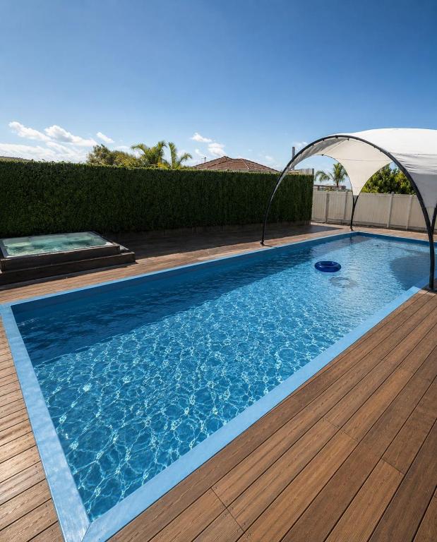 a large swimming pool with a wooden deck and an umbrella at אחוזת החושן - וילה מהממת עם בריכה פרטית in Tirosh