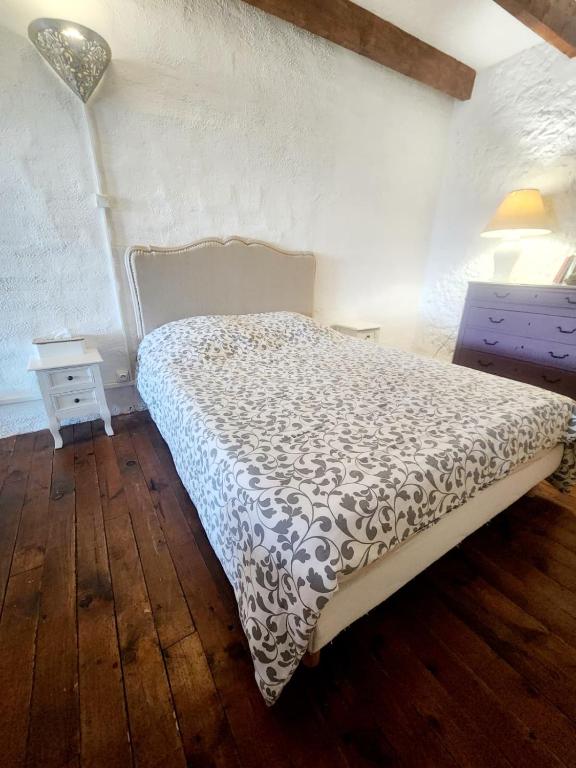 a bedroom with a bed with a black and white comforter at Le logis des vendangeurs in Puisserguier