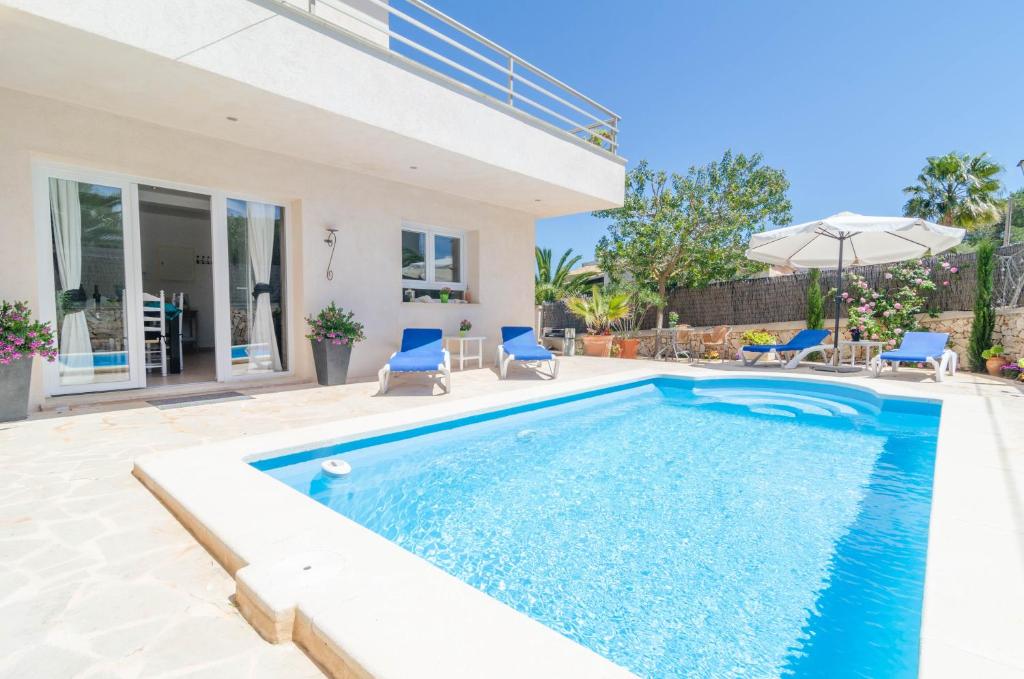a swimming pool with blue chairs and a house at Xalet S'Escaleta in Cala Santanyi