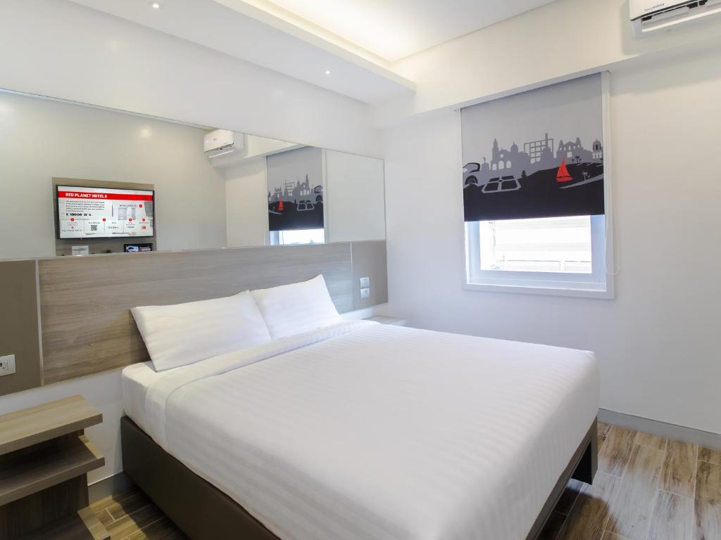 a bedroom with a large white bed and a tv at Red Planet BGC The Fort in Manila
