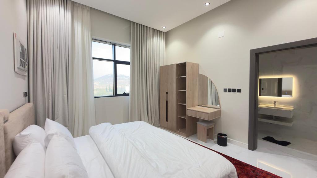 a white bedroom with a large bed and a sink at شقق ميلا الباحة الفاخرة in Al Baha