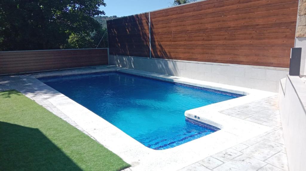 a swimming pool in a backyard with a wooden fence at Casa Abetos in Collado Mediano