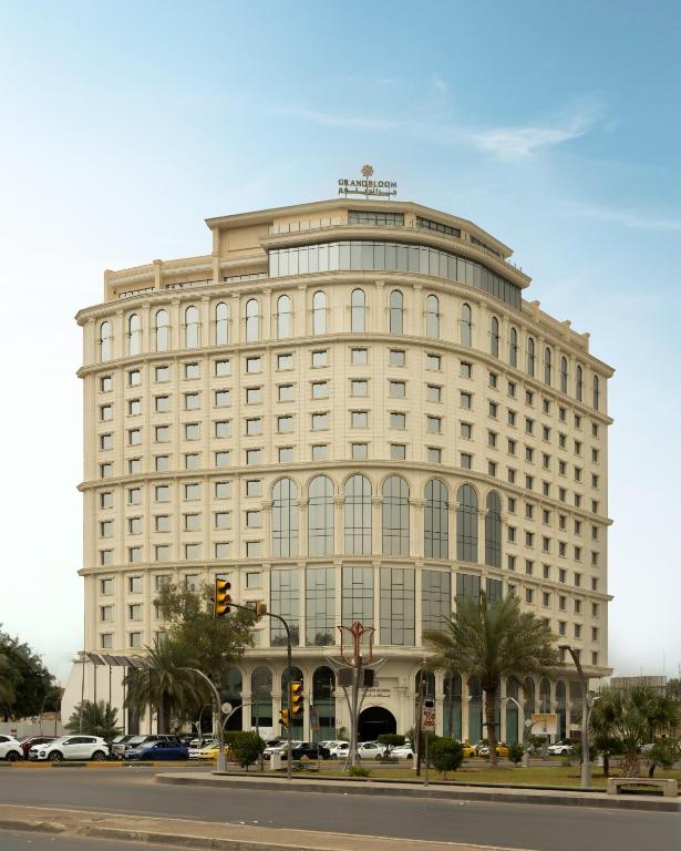 a large white building on the corner of a street at Grand Bloom Hotel in Baghdād