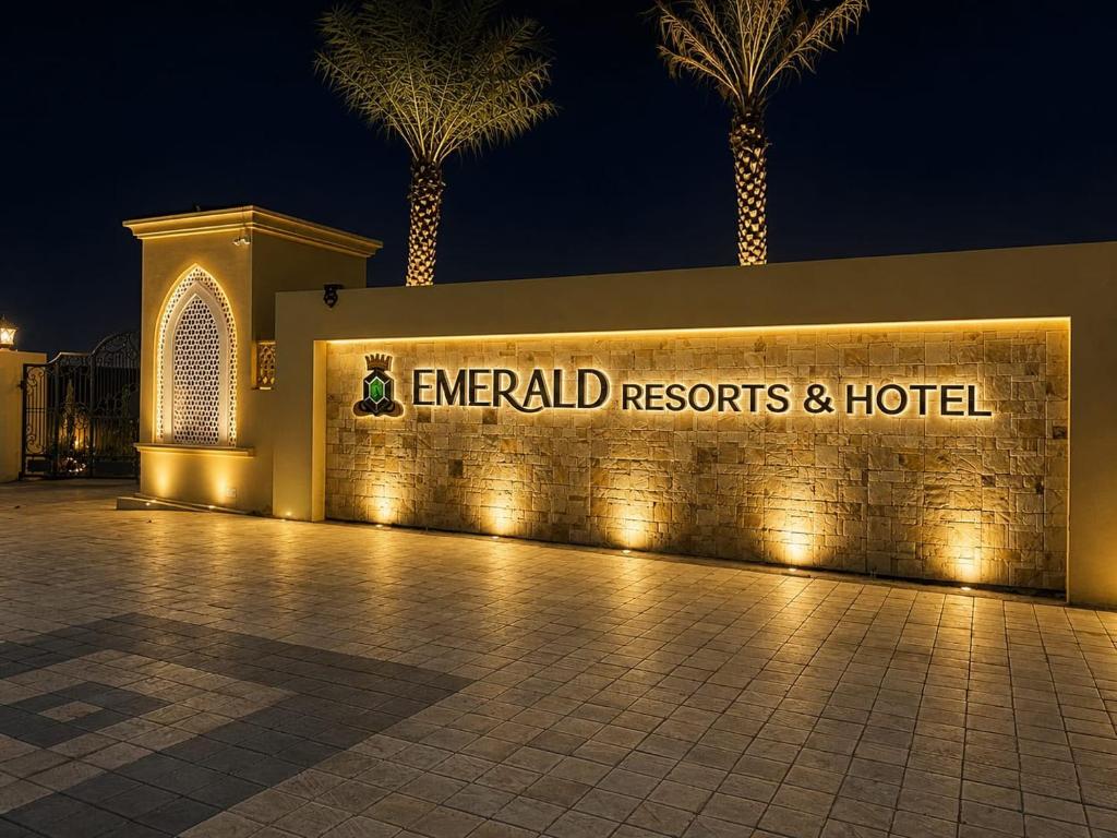 a sign for emerald resorts and a hotel with palm trees at Emerald Resorts and Hotel in Jāmb