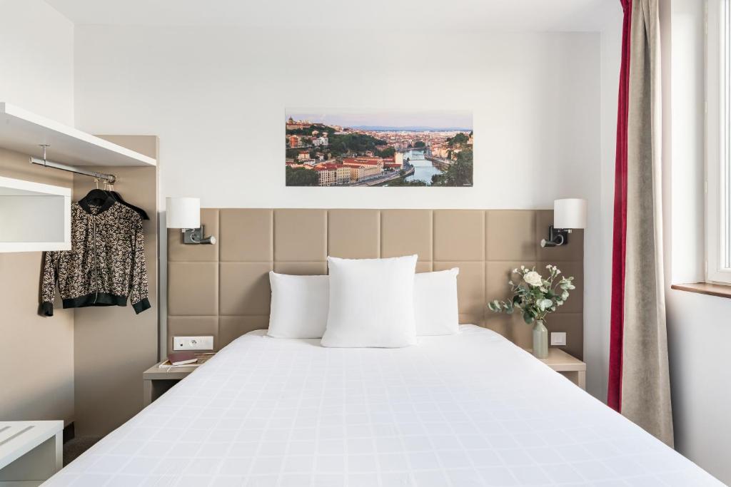 a bedroom with a large bed with white pillows at Kyriad Lyon Est Stadium Eurexpo Meyzieu in Meyzieu