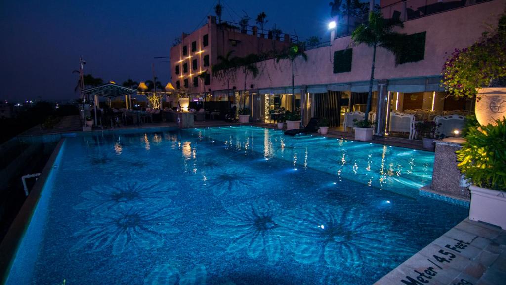 a swimming pool at night with blue lights on it at The Nagpur Ashok in Nagpur