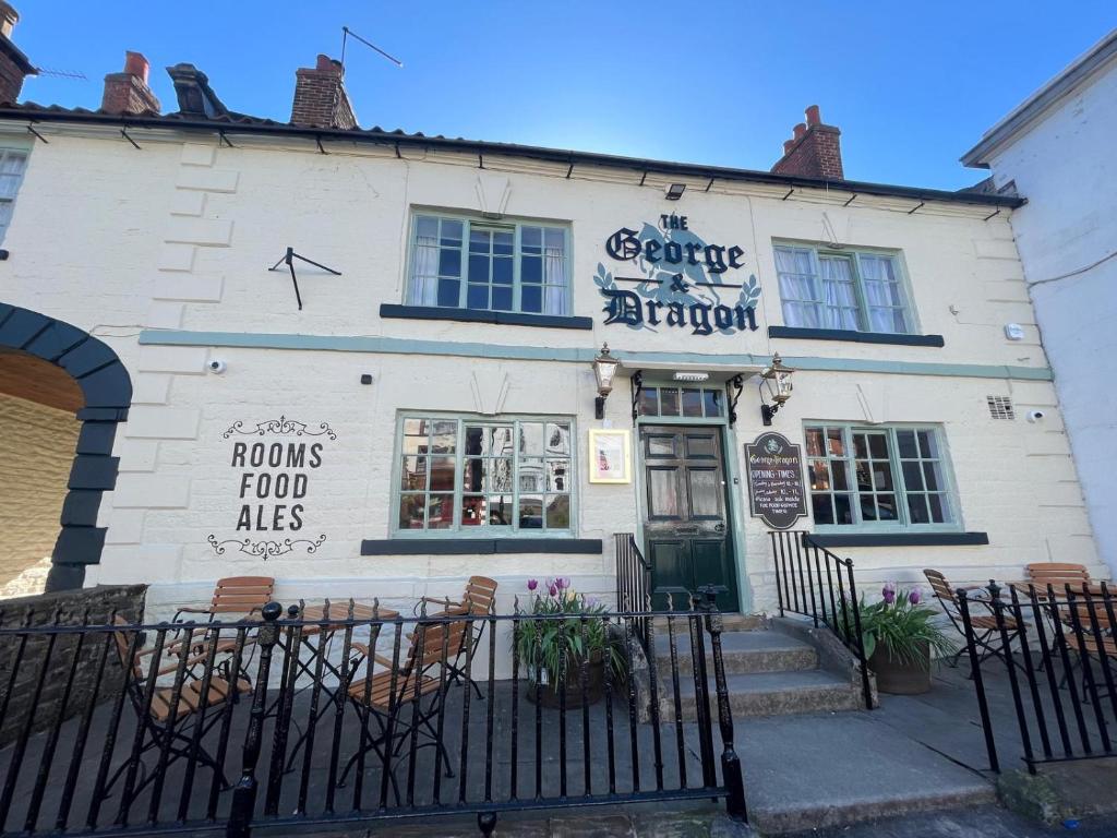 a white building with a fence in front of it at George & Dragon Hotel in Kirkbymoorside