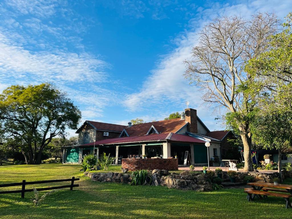 a house in a park with benches in the grass at BelofteBos Farmhouse Inn in Bandelierkop