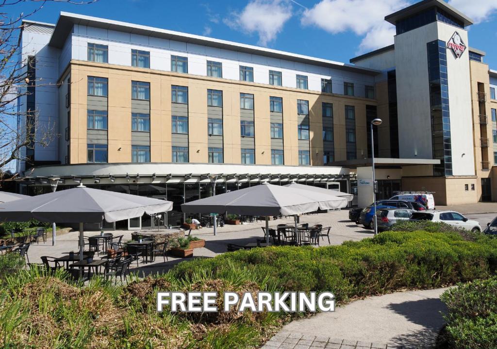 a building with tables and umbrellas in front of it at Future Inn Plymouth in Plymouth