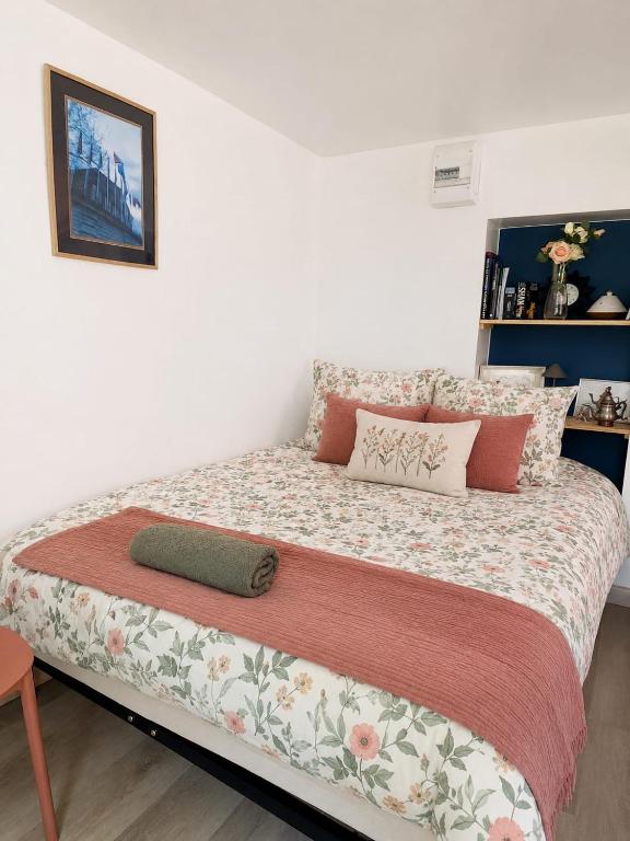 a large bed in a bedroom with a flower patterned blanket at Le Nid, petit studio cosy et central in Besançon