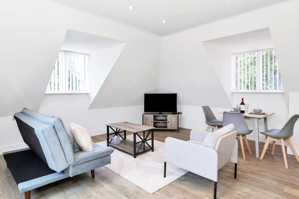 a living room with chairs and a tv and a table at Addenbrookes Apartment in Trumpington