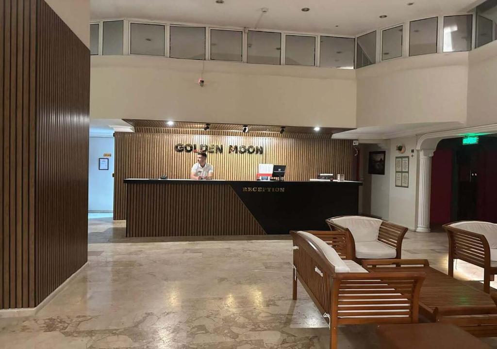 a woman standing at a counter in a lobby at Golden Moon Apart Hotel in Kuşadası
