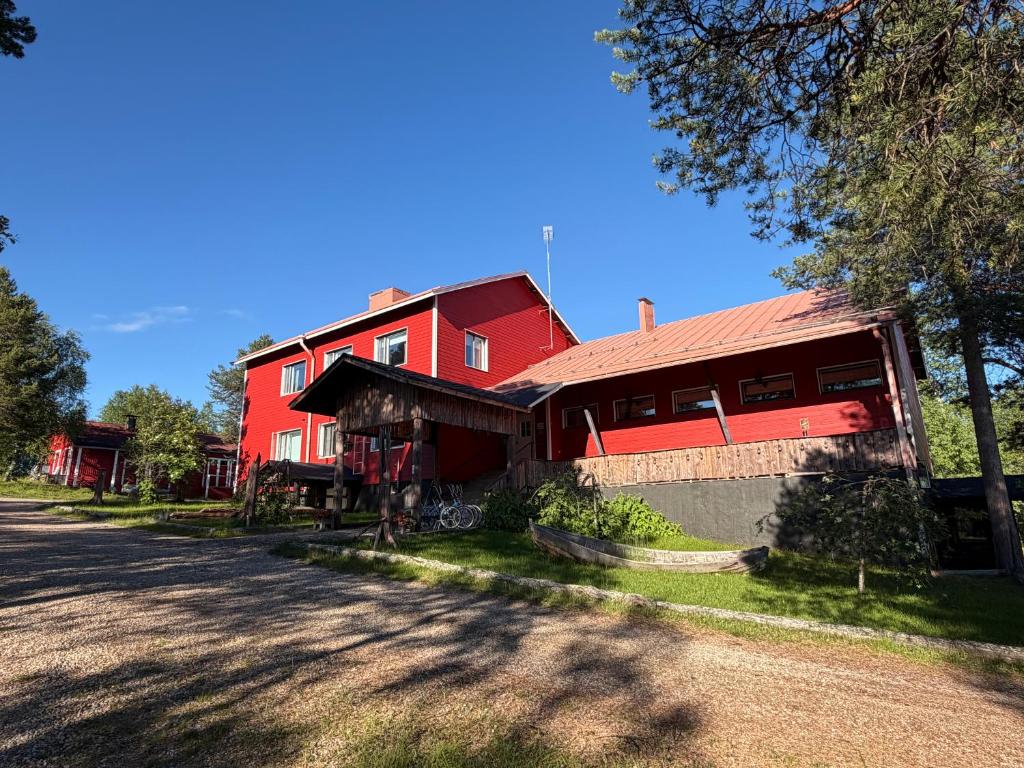 a red barn with a red roof on a road at Hotel Korpikartano in Inari