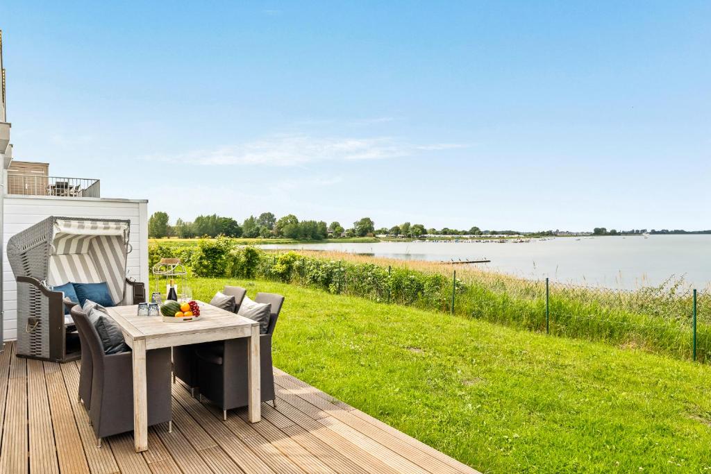 a table and chairs on a deck with a view of a lake at Ferienwohnung WeitBlick Olpenitz in Olpenitz