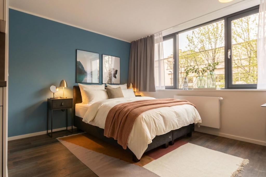 a bedroom with a bed with blue walls and windows at Limehome München in Munich