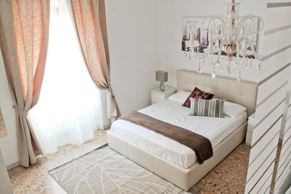 1 dormitorio con cama blanca y lámpara de araña en Nonna grazia, en Roma