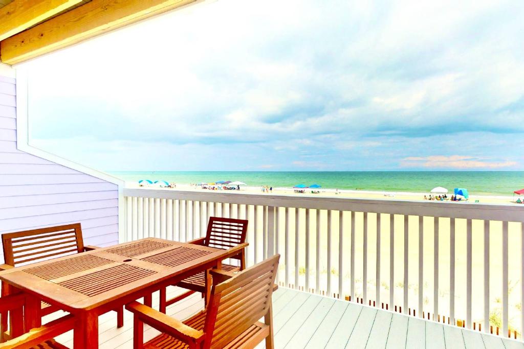 a balcony with a table and chairs and the beach at Dune Our Thing in Kure Beach