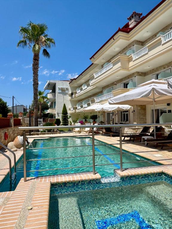 a swimming pool next to a building with a palm tree at Melis Studios in Kallithea Halkidikis