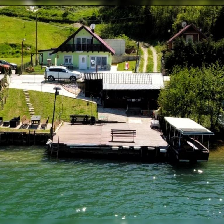 a dock in a body of water with a house at Villa sul lago in Jajce
