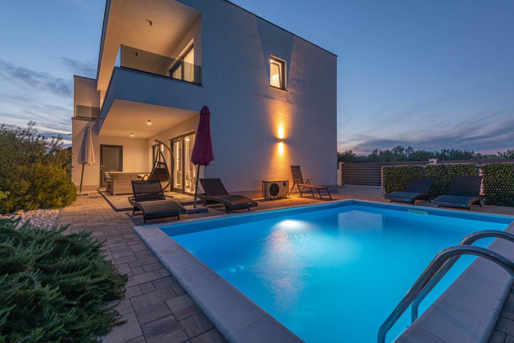 a swimming pool in front of a house at Villa Adriatic Sunrise in Šibenik
